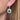 Close-up of an earring with a emerald and diamonds worn by a person.