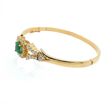 Angled top view of emerald and diamond bracelet in 18k yellow gold – luxury fine jewelry New Orleans