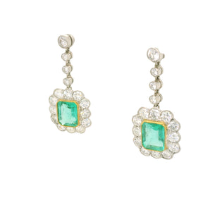 Pair of earrings with green emeralds  and white diamond  accents on a white background