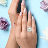 Hand wearing a pearl ring with flowers on a light blue background