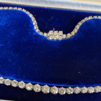 Close-up of European cut 24.00ct diamond Riviera necklace in blue velvet presentation box