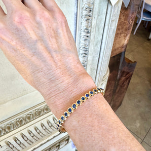 Blue sapphire bracelet worn on wrist – elegant New Orleans jewelry design in yellow gold